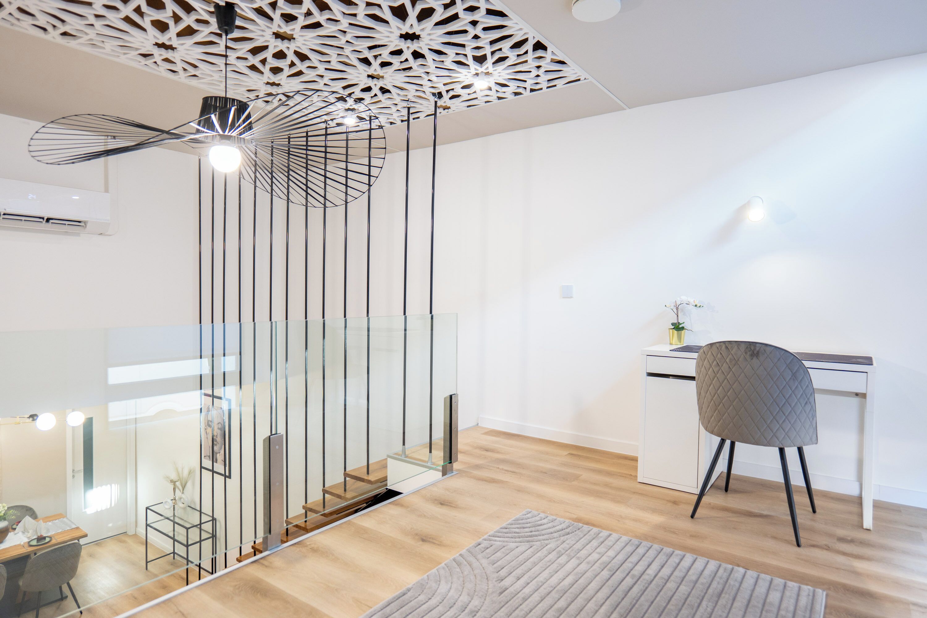 Een modern interieur met een glazen trap, een bureau en een stoel.