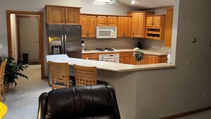 Una cocina moderna con armarios de madera, electrodomésticos de acero inoxidable y una isla central con taburetes de bar.