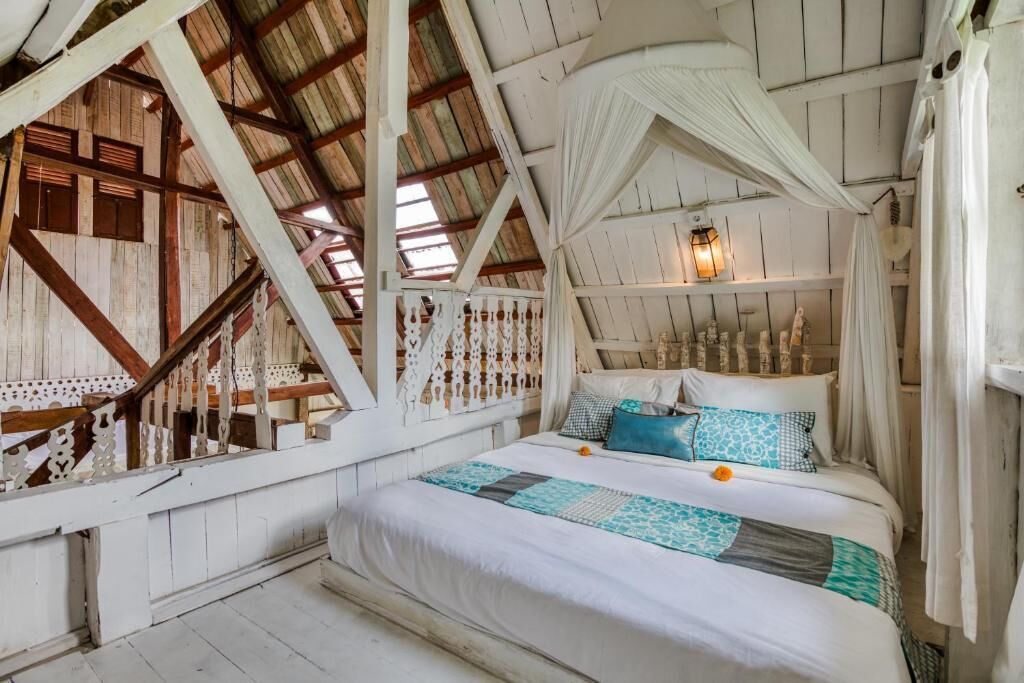 A rustic room with a bed, white curtains, and a hanging light fixture.