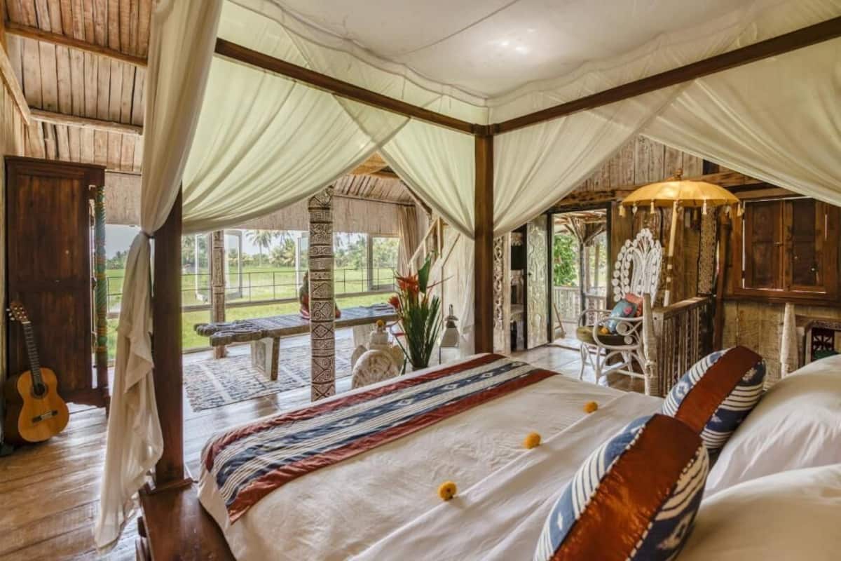 Una stanza con un letto, una chitarra e vista sull'esterno.