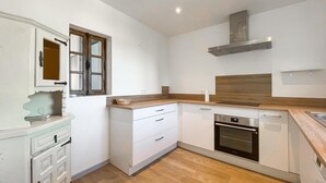 Eine moderne Küche mit weißen Schränken, einem eingebauten Ofen und einer Holz Arbeitsplatte.