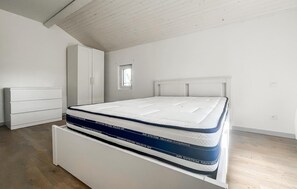 Un dormitorio con cama, armario y una ventana pequeña.
