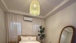 A modern bedroom with a wooden bed, a large mirror, and a hanging light fixture.