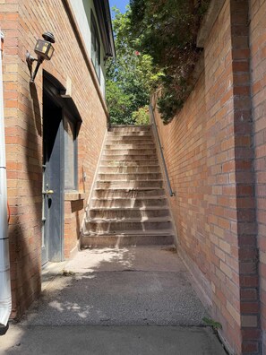 A narrow brick stairway leading to a building entrance, with a metal handrail and a door with a keyhole. - 2B2b loft in mountains, secluded patio, vintage, (Ogden)