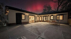 A house with a covered patio, multiple doors, and windows with lights.