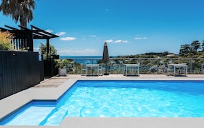 Una piscina al aire libre, sombrillas, sillones reclinables de piscina