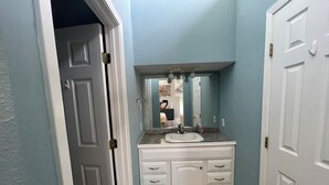 Een badkamer met een wit wastafelmeubel, een wastafel en een spiegel.