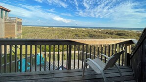 Een houten terras met uitzicht op het strand en de duinen.
