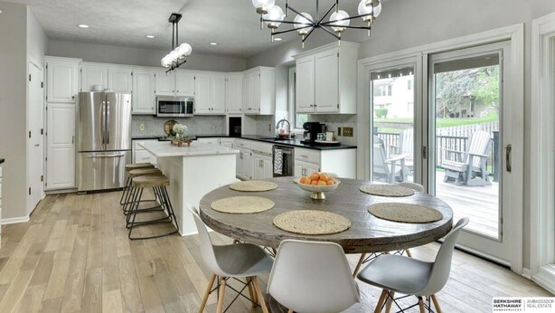 Una cocina moderna con armarios blancos, electrodomésticos de acero inoxidable y una isla central con asientos.