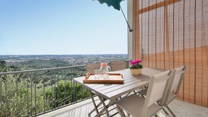 Een balkon met een tafel en stoelen, uitzicht op een stadslandschap en een houten hek.