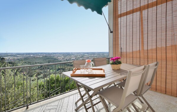 A balcony with a table and chairs, a view of a cityscape, and a wooden fence.