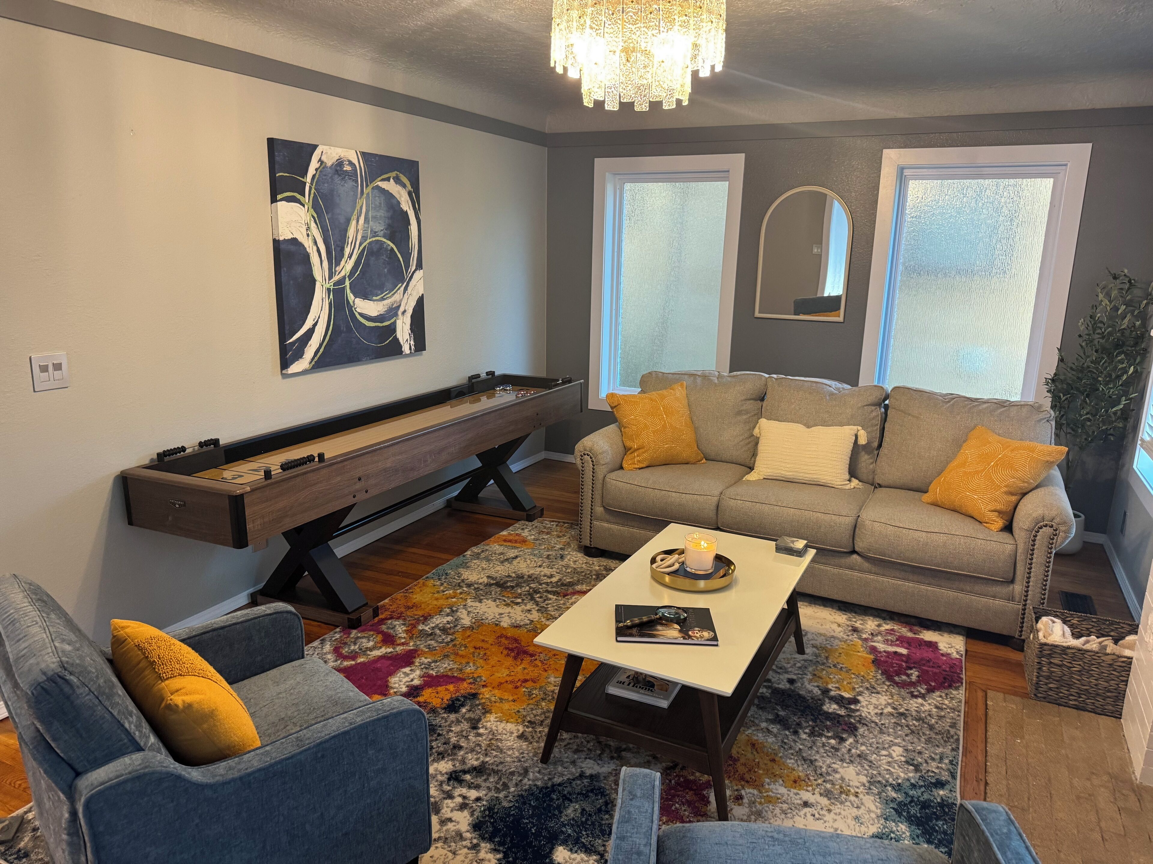 A living room with a foosball table, a sofa, a coffee table, and a colorful rug.