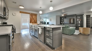 A modern kitchen with a central island, stainless steel appliances, and a large window.