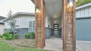 A house entrance with a covered porch, a wooden door, and a garage door.