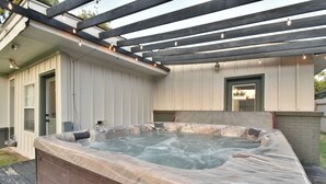 A hot tub in a covered outdoor area with wooden beams and string lights.