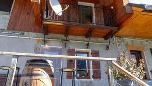 Un edificio in legno con un balcone, un'antenna parabolica e una botte.