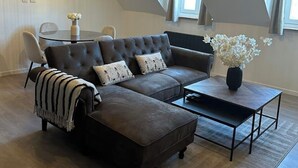 Een moderne loft slaapkamer met een ruime zithoekbank, een salontafel en een hanglamp.