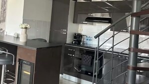 Een moderne keuken met een centraal eiland, roestvrijstalen apparatuur en een spiltrap.