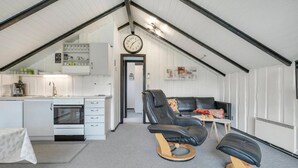 Quarto compacto e moderno estilo loft, com cozinha compacta, sofá de couro preto e uma pequena mesa.