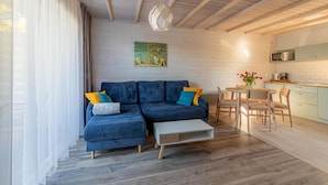 Ein modernes Wohnzimmer mit einem blauen Sofa, einem kleinen Couchtisch und einem Essbereich mit einem runden Tisch und Stühlen.