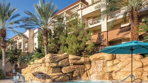 Ein Hotel mit Poolbereich, Palmen und Felslandschaft im Hintergrund.