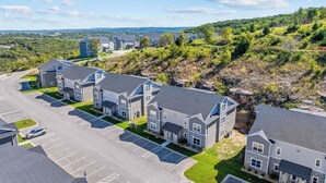 A residential area with multiple two-story houses, a parking lot, and a hilly landscape in the background. - Perfect Location! Near SDC, Branson Strip & Lake (Branson)