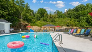 A swimming pool with inflatable toys, lounge chairs, and a covered seating area. - Perfect Location! Near SDC, Branson Strip & Lake (Branson)