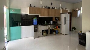A spacious kitchen with white tiled floors, wooden cabinets, and stainless steel appliances.