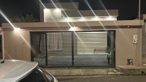 A modern building with a gated entrance and a white car parked in front.