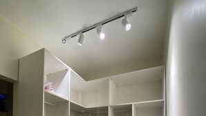 A walk-in closet with multiple shelves and drawers, a ceiling track lighting system, and a tiled floor.
