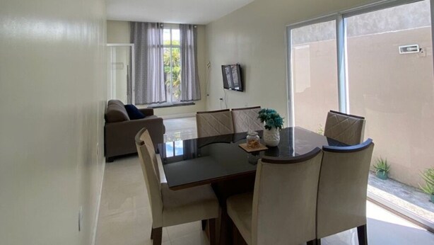 A dining area with a table and chairs, a chandelier, and a view of the outside.