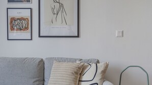 Een woonkamer met een grijze bank, een kleine tafel en een groene stoel. Drie kunstwerken hangen in de lijst op de muur.