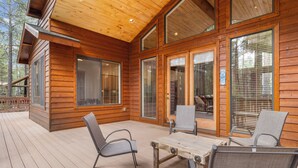 Une cabane en bois dotée d’une terrasse, de grandes fenêtres et d’un espace salon extérieur.
