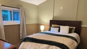 A bedroom with a wooden bed, a nightstand, a lamp, and a window with curtains. - Newly renovated 3-bedroom 2 bath pet friendly unit on Barclay Mountain. (Monroe)