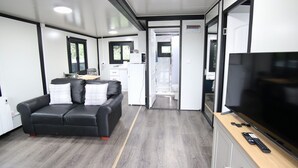 Een knus woongedeelte met een bank, een televisie en een kitchenette.