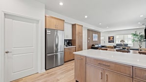 A modern kitchen with wooden cabinets, a stainless steel refrigerator, and a large island. - The Stadium Getaway (Lexington)