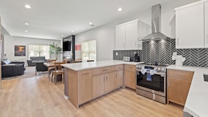 A modern kitchen with wooden cabinets, a stainless steel range hood, and a herringbone-patterned backsplash. - The Stadium Getaway (Lexington)