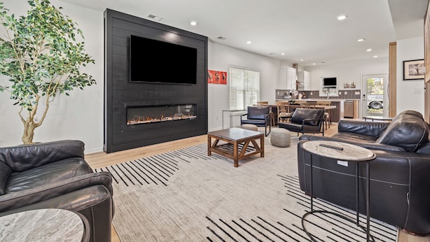 A modern living room with a fireplace, leather sofas, and a dining area. - The Stadium Getaway (Lexington)