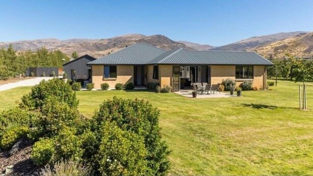 A modern two-story house with a flat roof, a covered patio, and a well-maintained lawn. - Modern private suite on local cherry orchard (Cromwell)