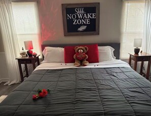 A bedroom with a bed, a teddy bear, and a sign that says "Shhh... NO WAKE ZONE".