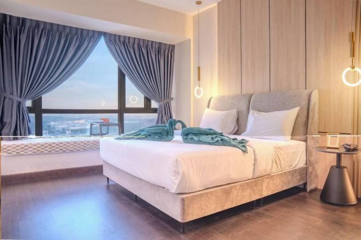 A modern hotel room with a large bed, a view of the city, and a round light fixture.