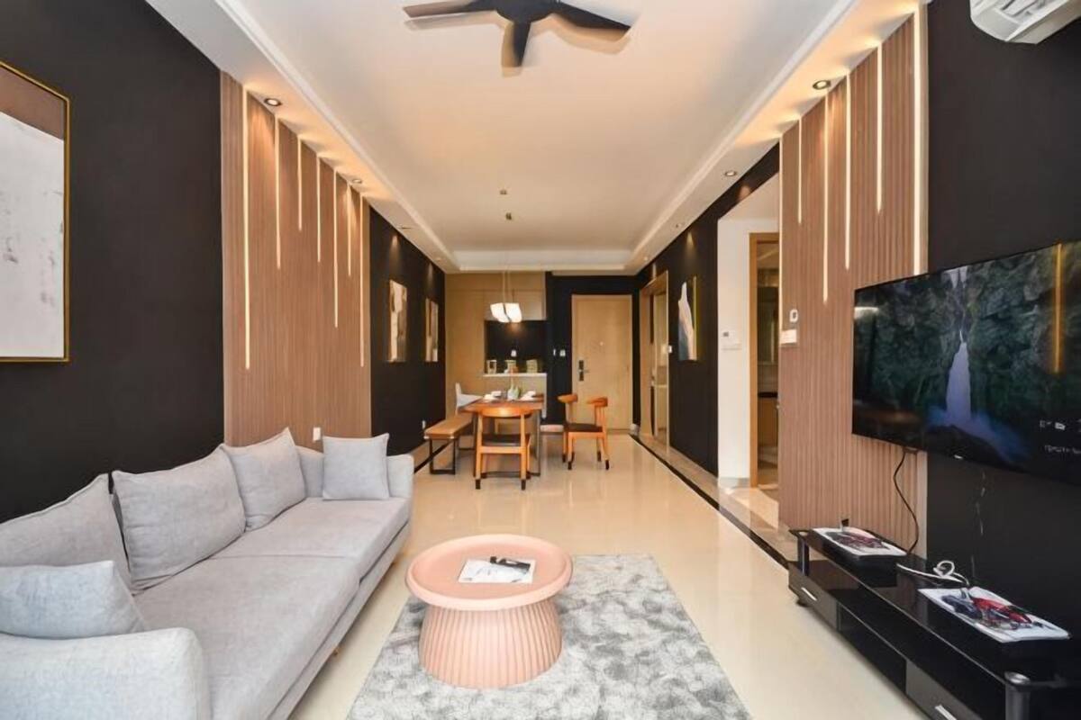 A modern living room with a sofa, coffee table, TV, and dining area.