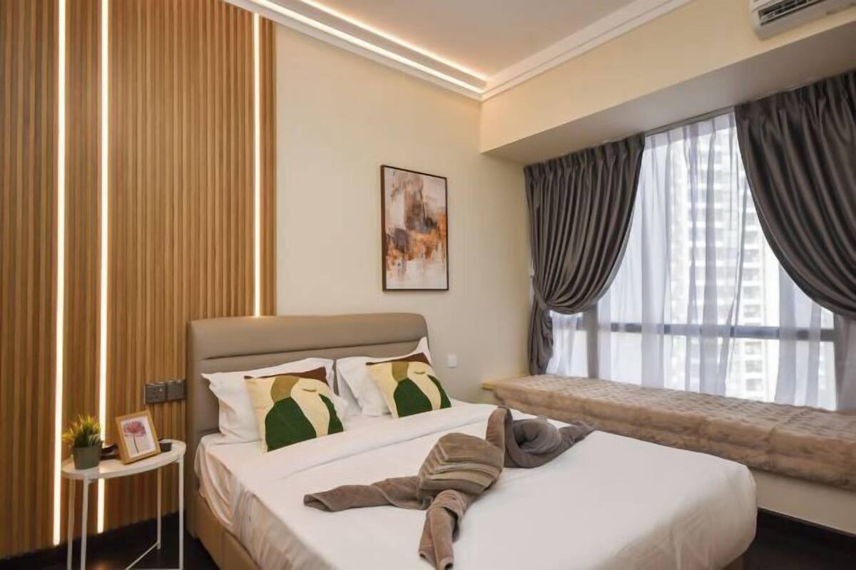 A hotel room with a bed, bedside table, artwork, and a window with curtains.