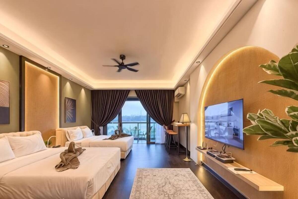 A hotel room with two beds, a TV, a ceiling fan, and a view of the outdoors.