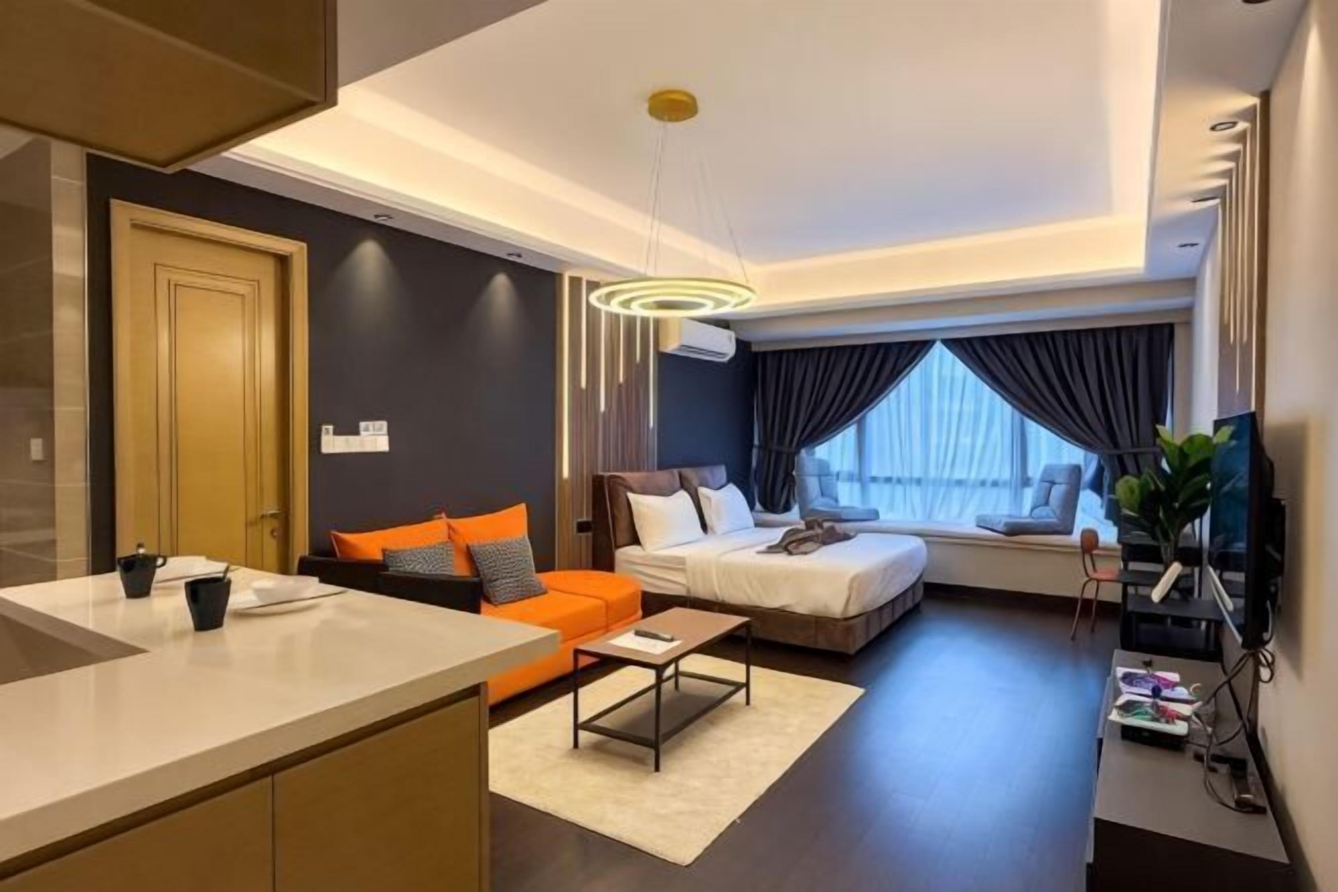 Una habitación de hotel moderna con kitchenette, un sofá, una cama y un ventanal grande.