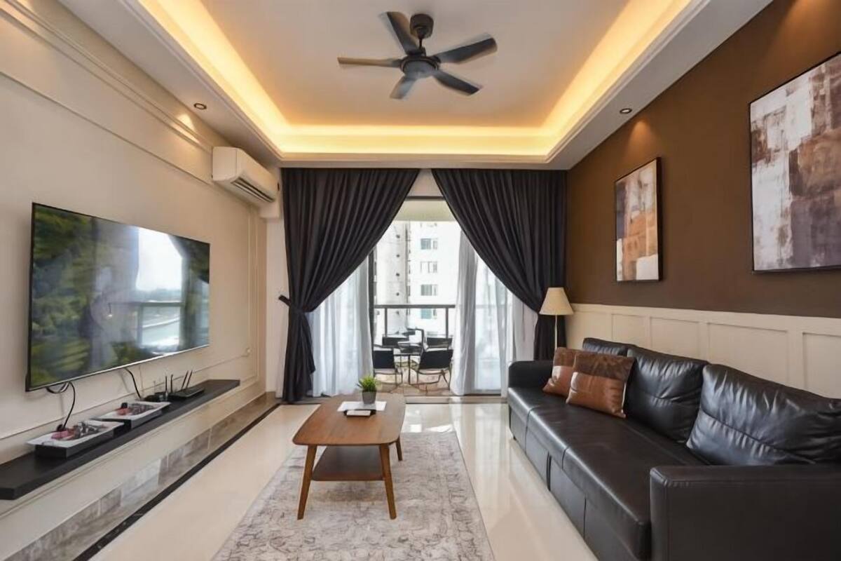 A modern living room with a flat-screen TV, a ceiling fan, a sofa, a coffee table, and a view of the outdoors.