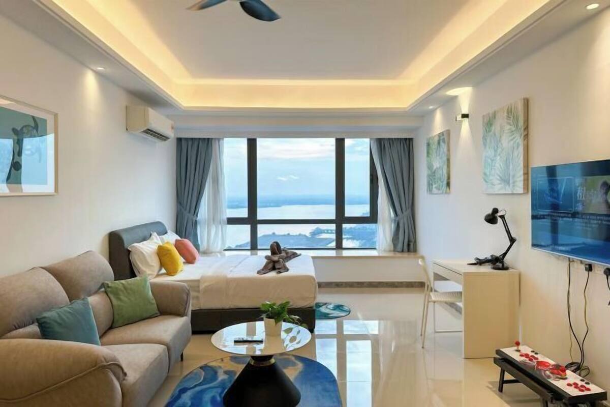 A modern living room with a sofa, a coffee table, a TV, and a large window with a view.