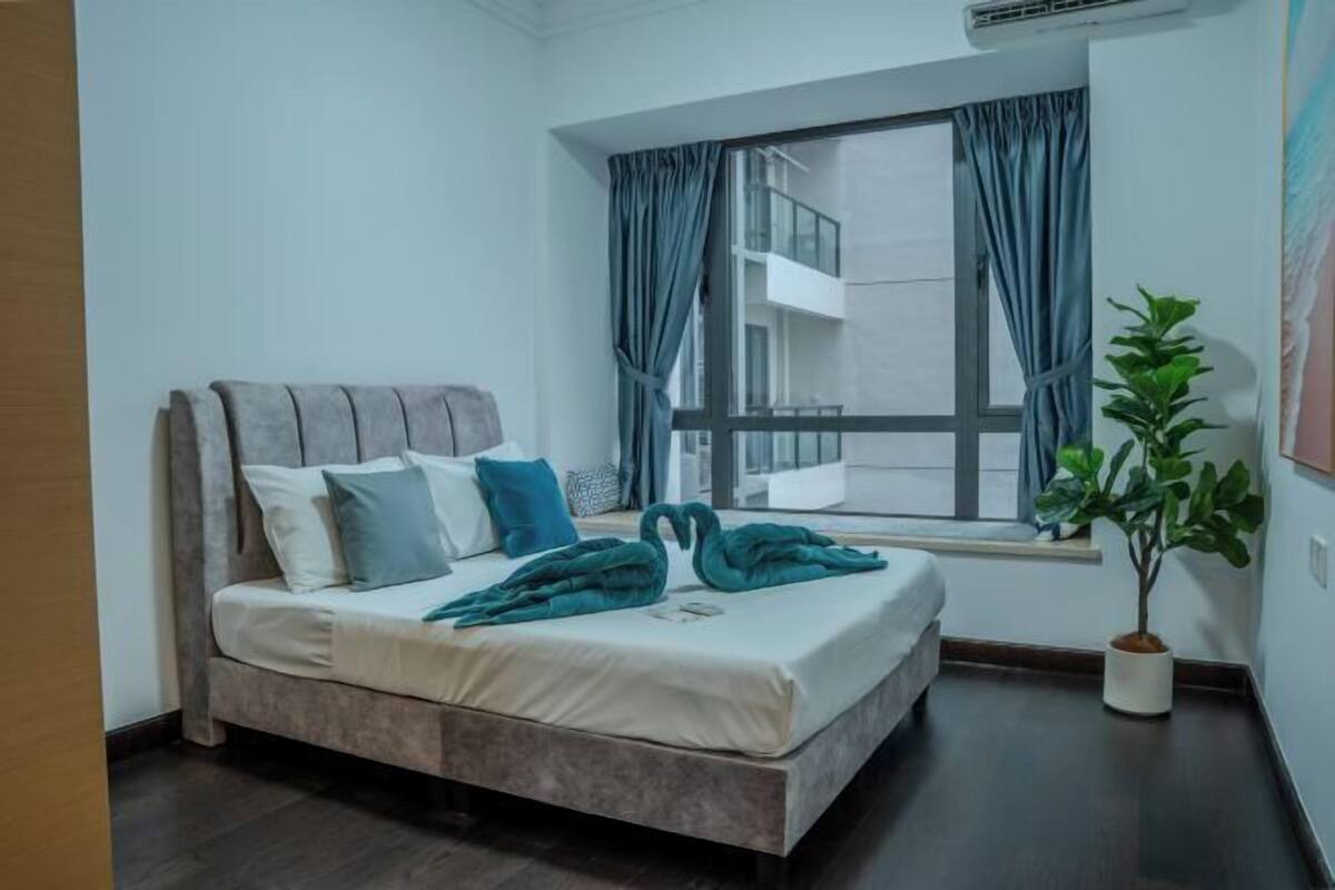 A bedroom with a bed, curtains, a window, and a potted plant.