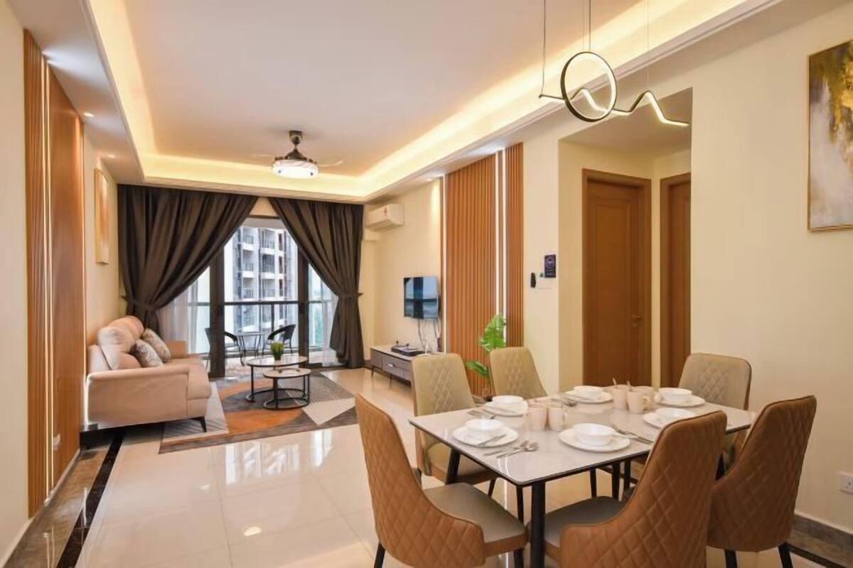 A modern hotel room with a dining area, a sofa, a TV, and a large window.