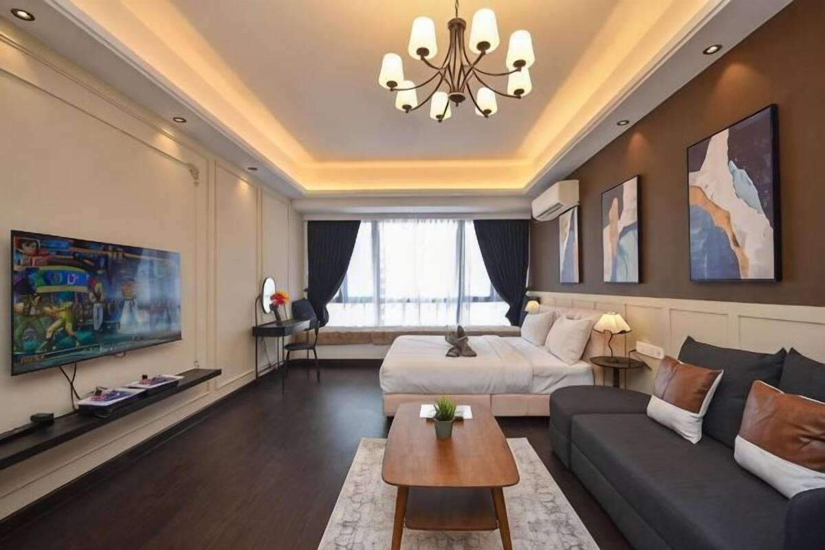 A modern hotel room with a large bed, a sofa, a TV, and artwork on the walls.
